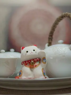 A maneki-neko beside a white tea set